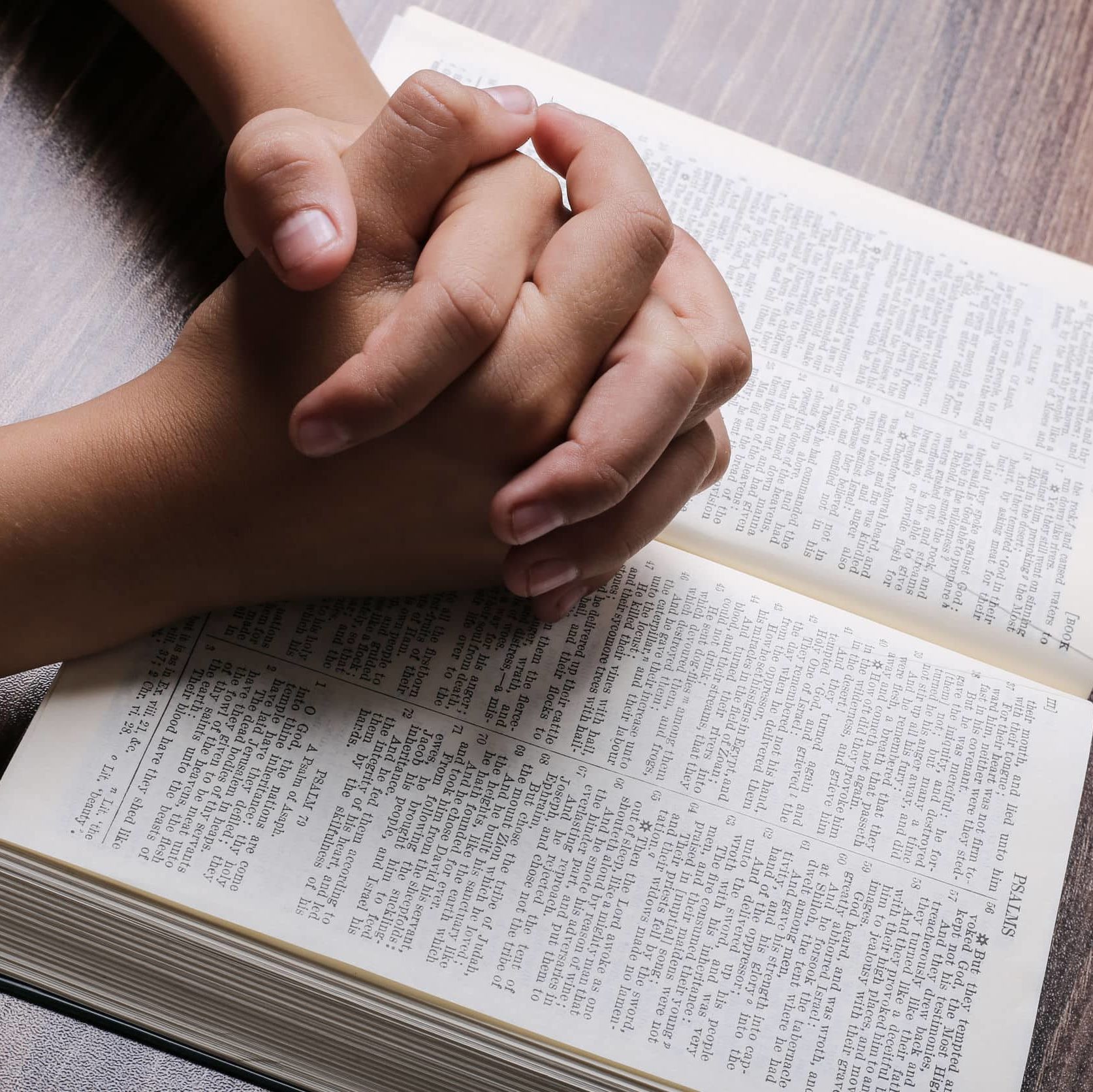 Praying Hands With Holy Bible Praying hands with opened holy bible on the wooden desk.